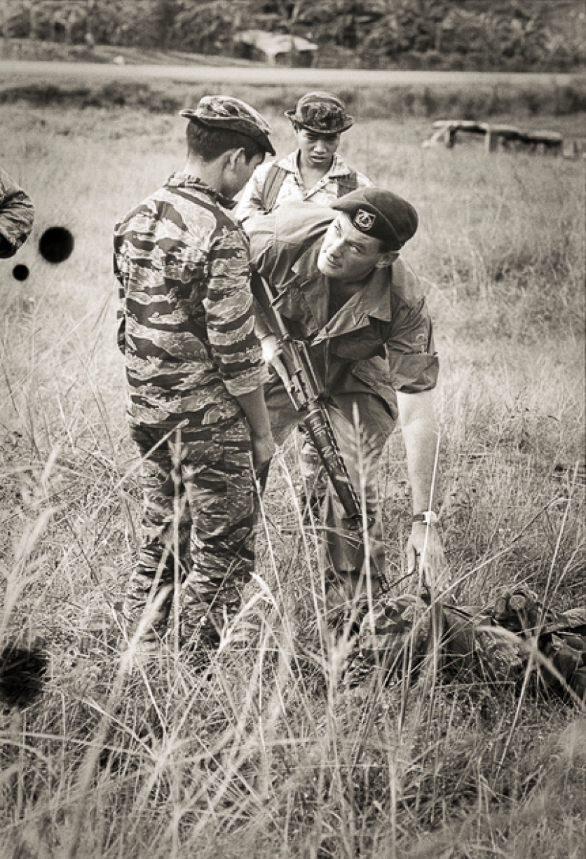 "This is how you do it." Warrant Officer Class 2 (WO2) Lachlan Scowcroft of Holsworthy, NSW, shows one of his Montagnard soldiers how to search a captured enemy. Scowcroft joined Shilston's 211 Company on the second day of their attempt to break the siege of Dak Seang in April 1970. Photo: Christopher Bellis. Australian War Memorial Accession Number: BEL/69/0696/VN