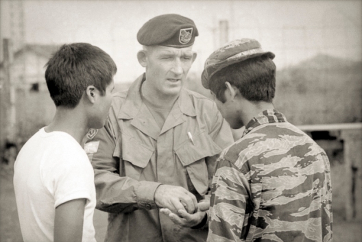Pleiku, South Vietnam. 1969-10. Warrant Officer Class 2 (WO2) Alex McCloskey of Newcastle, NSW, explains a point to a Montagnard soldier of the II Corps Mobile Strike Force (Mike Force). McCloskey would be awarded the Distinguished Conduct Medal (DCM) for his actions during the action to break the siege of Dak Seang in April 1970. Photo: Christopher Bellis. Australian War Memorial Accession Number: BEL/69/0702/VN