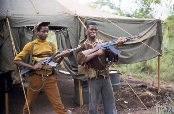 Op AGILA: Two guerillas display their Kalashnikov AK 47 weapons at Assembly Area Foxtrot, near the Rhodesian border with Mozambique, during the seven day ceasefire at the start of the peace process. During the ceasefire, 22,000 communist guerrilla fighters of Robert Mugabe's Zimbabwe National Liberation Army (ZANLA) and Joshua Nkomo's Zimbabwe People's Revolutionary Army (ZIPRA) gathered at sixteen assembly points in the lead up to the elections. Copyright: © IWM. Original Source: http://www.iwm.org.uk/collections/item/object/205191111